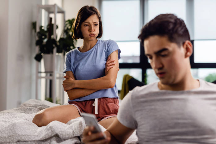 Stressed out woman with arms crossed frowning at her boyfriend.