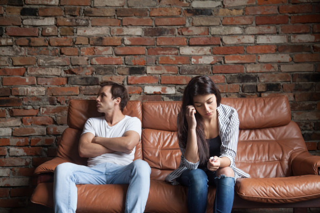 frustrated-upset-couple-after-quarrel-sitting-sofa-home_1163-4450