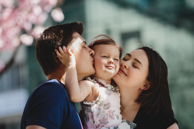 happy-young-parents-with-little-daughter-stand-blooming-pink-tree-outside_8353-7690